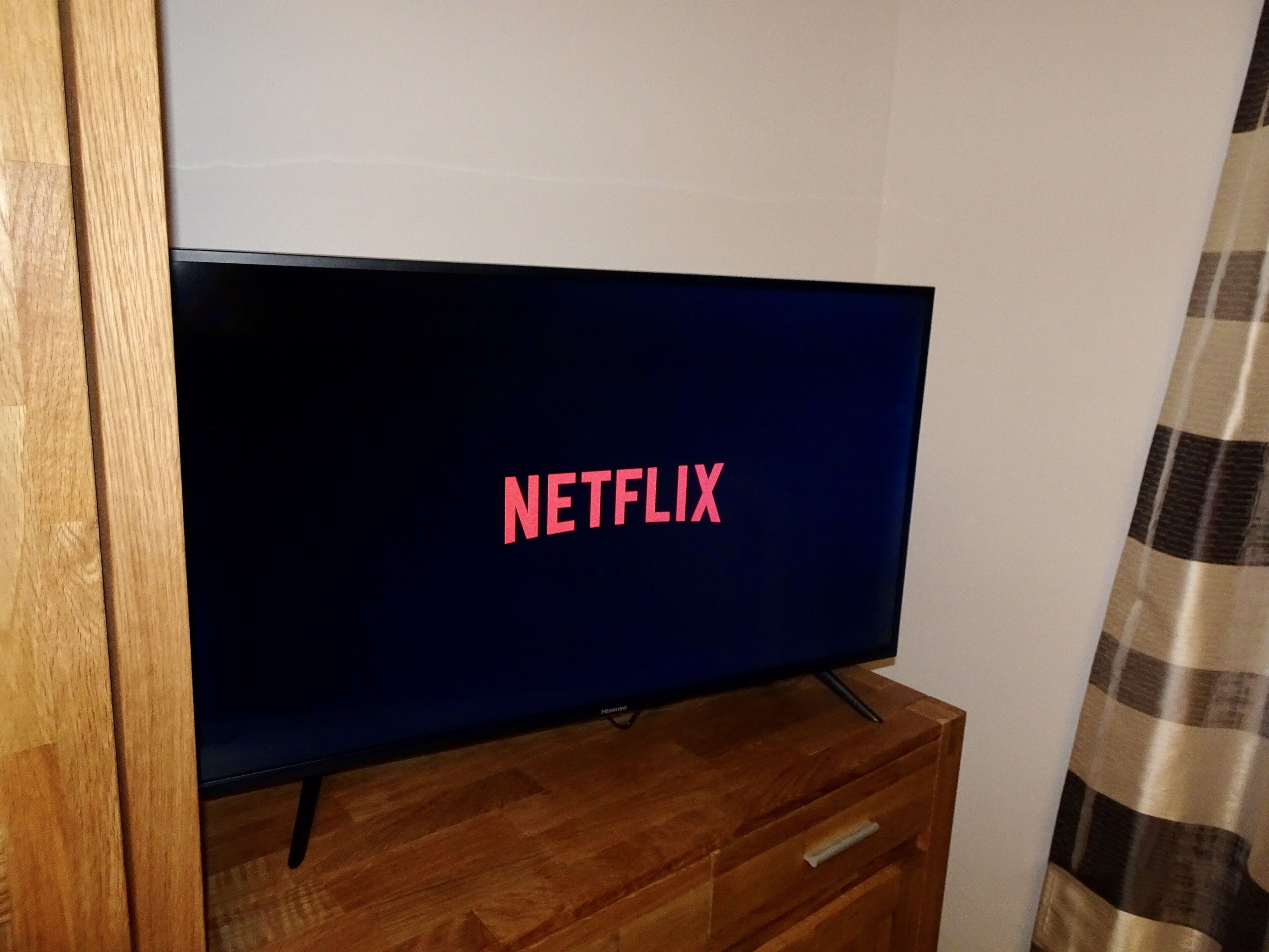 A television on a wooden dresser with the Netflix logo displayed on the screen.