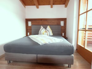 A bed with a grey mattress, wooden headboard, and striped pillows.
