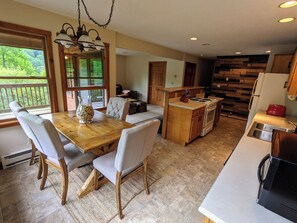 A spacious kitchen with a dining area, wooden cabinets, and a view of the outdoors. - Large lodge w/ game room, fire pit + private suite (Slaty Fork)
