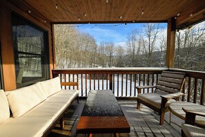 Une terrasse extérieure couverte, avec un banc en bois, un canapé et une table.
