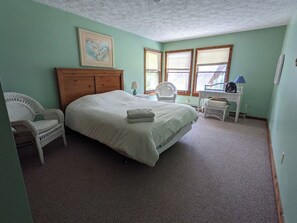 Une chambre à coucher avec un lit, deux chaises, une table de chevet et une fenêtre.