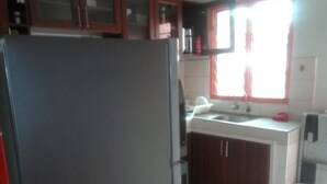 A kitchen with a refrigerator, cabinets, a sink, and a window. - Rokas Hotel (Migori)