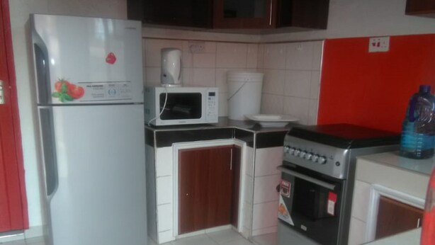 A compact kitchen with a refrigerator, microwave, stove, and sink. - Rokas Hotel (Migori)