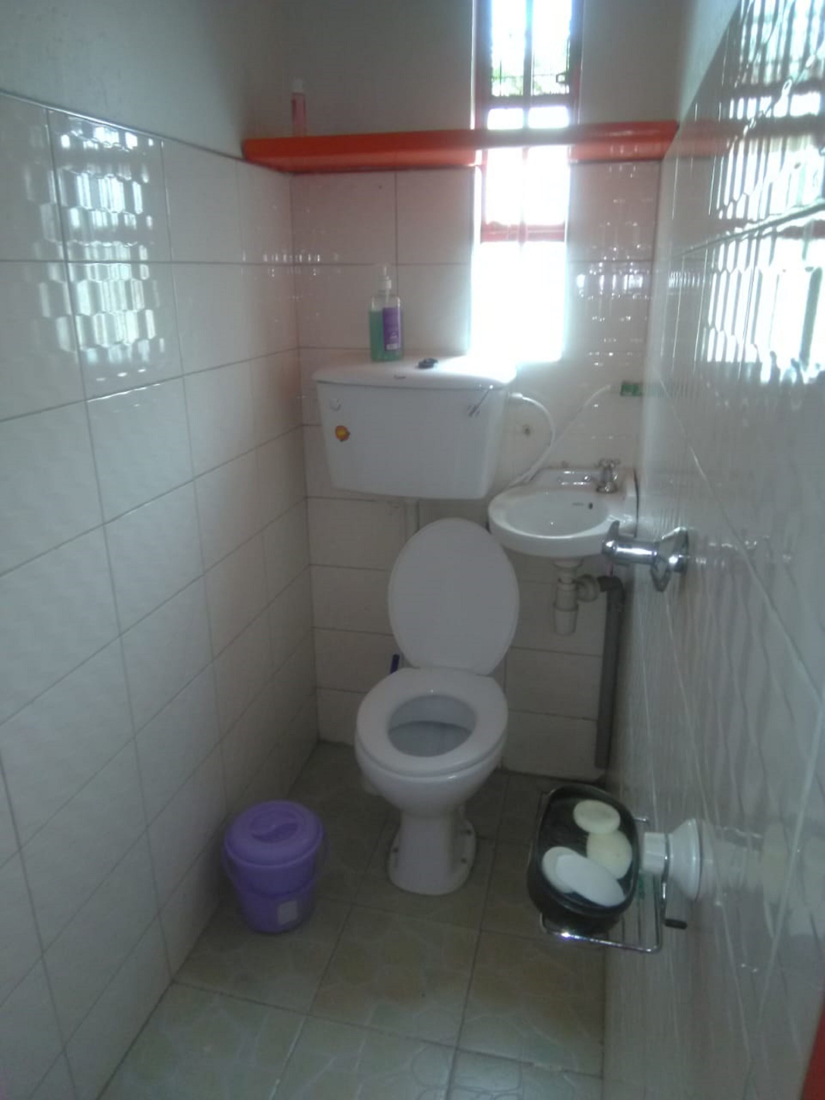 Et lille badeværelse med toilet, vask og et vindue.