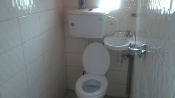 Une petite salle de bain avec des toilettes, un lavabo et une fenêtre.