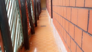 A corridor with tiled flooring, brick walls, and metal railings. - Rokas Hotel (Migori)