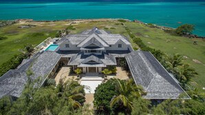 A large, two-story house with a symmetrical roof design, a swimming pool, and a view of the ocean. - Barbados Luxury Ocean Front Villa ~ 7 Bedroom Suites ~ 7 Private Bathrooms (St Philip)