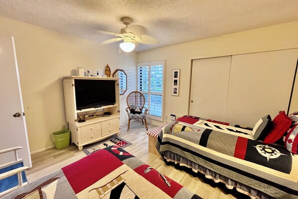 A bedroom with a bed, a TV, a chair, and a window. - FREE FUN Included Every Day! To enhance your perfect Gold-rated vacation just steps away from the beautiful beach!! (Saint Augustine)
