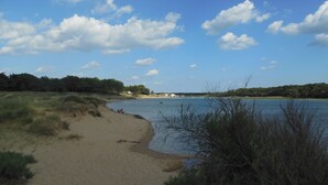 A sandy beach with a clear blue sky and scattered clouds.
