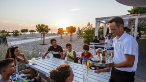 A group of people dining at an outdoor table with a waiter serving drinks. - 3 * apartments / 2pax studio (Zaton)