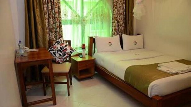 A hotel room with a bed, a desk, and a chair. - Comfy Bar And Restaurant (Nairobi)