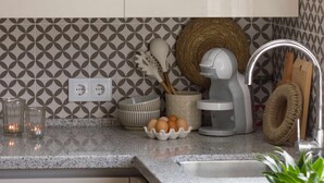 Una cocina con encimera de granito, una tetera blanca, un bol de huevos y una planta en maceta.