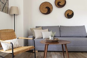A living room with a grey sofa, a wicker chair, a round wooden table, and a floor lamp. - Tourist Accommodation: Country House A (Alberca, La)