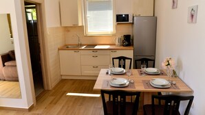 Una cocina compacta con una mesa de madera preparada para dos personas, un fregadero y un microondas.