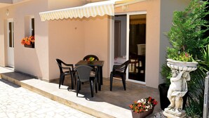 Un patio con una mesa y sillas, una planta en maceta y una estatua.