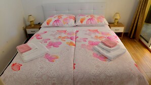 Una cama doble con ropa de cama floral, dos mesitas de noche con lámparas y vistas de la habitación.