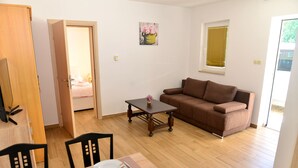 Una sala de estar con un sofá marrón, una mesa de centro de madera y una mesa de comedor dispuesta con platos y vasos.