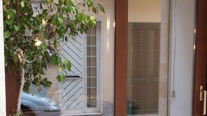 A sliding glass door entrance with a potted plant on the left. - Aristogatti (Ragusa)