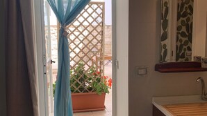A bathroom with a sink, mirror, and a door leading to an outdoor area with a lattice and potted plants. - Aristogatti (Ragusa)