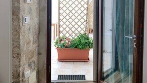 A doorway leading to a balcony with a potted plant and a wooden lattice. - Aristogatti (Ragusa)