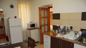 Cocina compacta con refrigerador, microondas y armarios de madera.