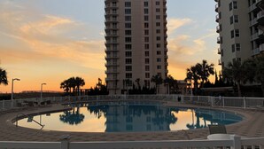 Ein Poolbereich mit Liegestühlen und einem hohen Gebäude im Hintergrund.