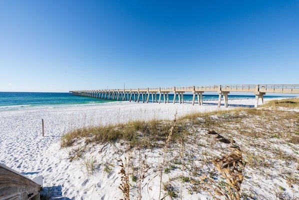 A beach with a wooden pier extending into the ocean.