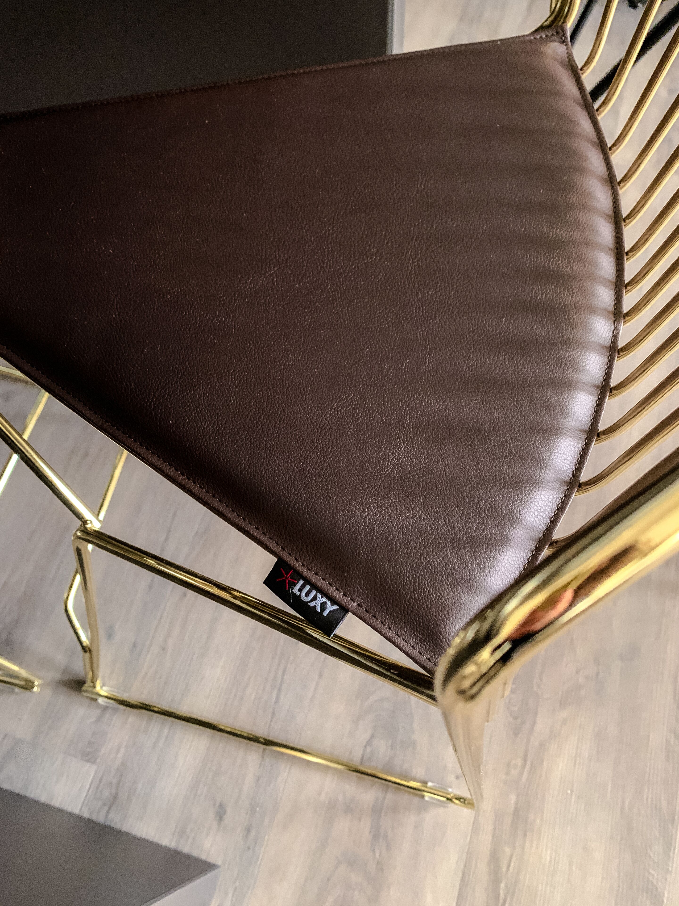 Una silla con asiento de cuero marrón y estructura de metal dorado.