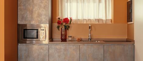 A modern kitchen with a built-in microwave, a sink, and a window with sheer curtains.
