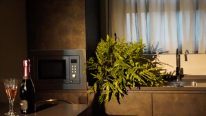 Una cocina con microondas, un lavamanos y una planta en maceta.