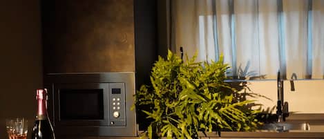 Une cuisine équipée d’un four à micro-ondes, d’un évier et d’une plante en pot.