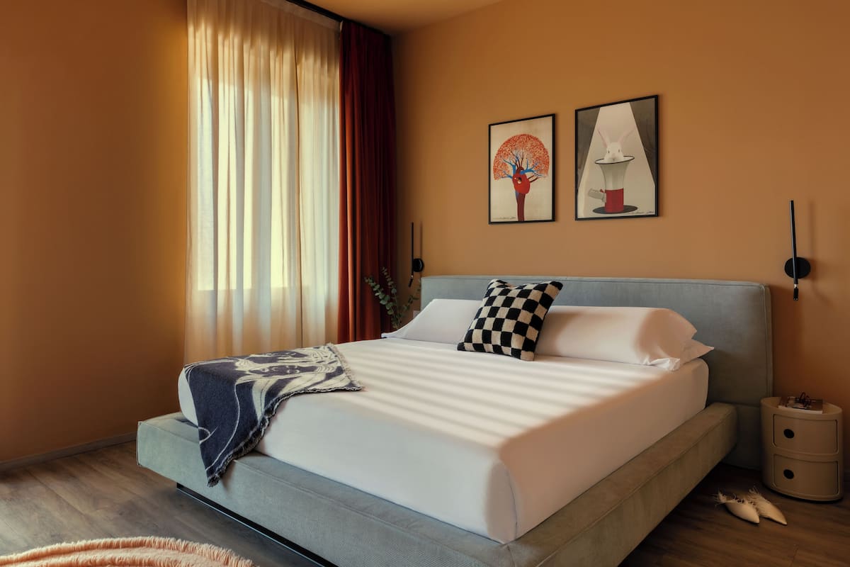 Une chambre à coucher moderne avec un grand lit, une table de chevet et deux lampes fixées au mur.