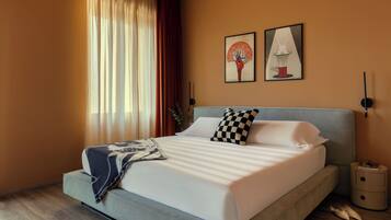 A modern bedroom with a large bed, a side table, and two wall-mounted lamps.