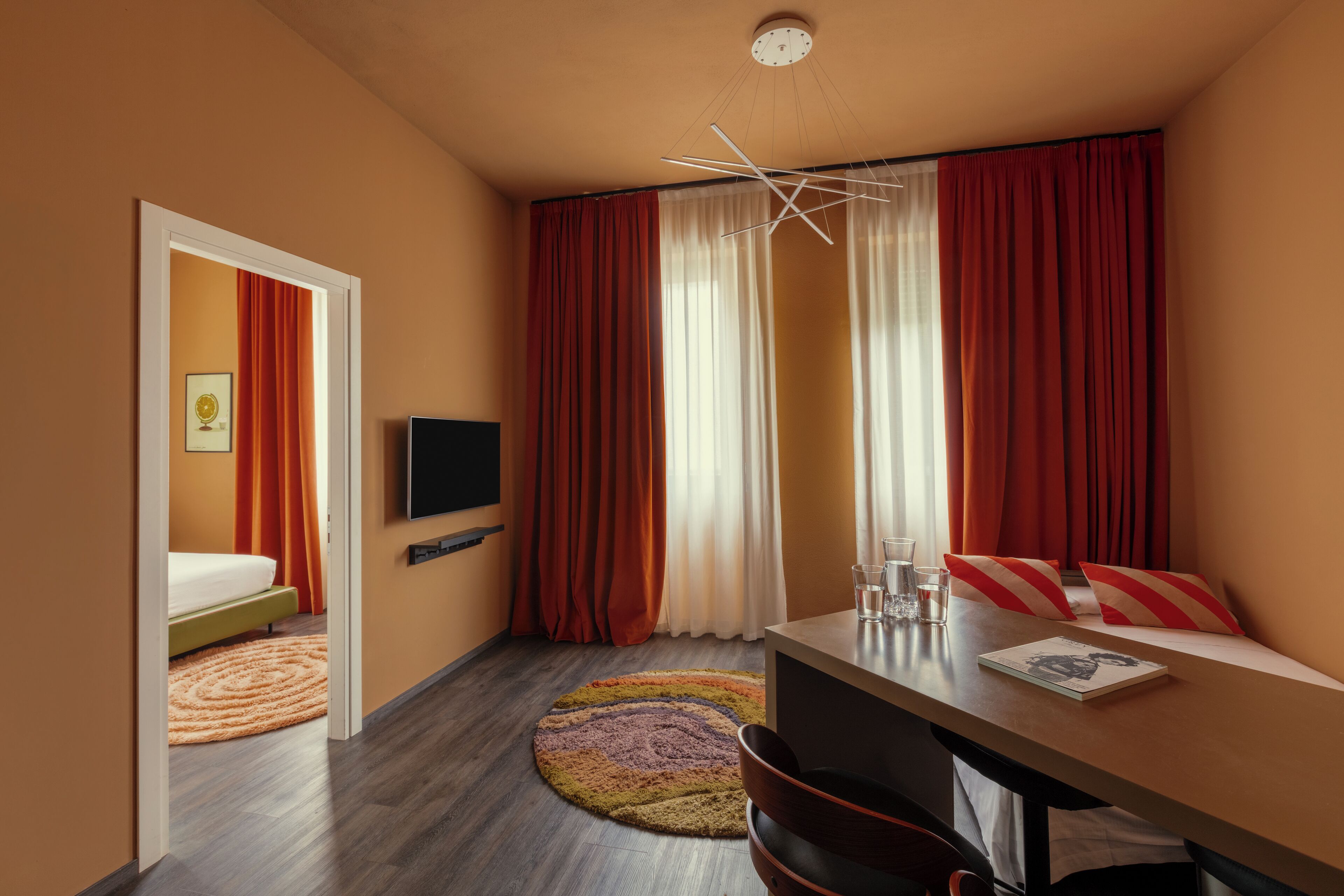 A compact hotel room with a bed, a desk, a television, and a window with curtains.