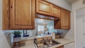 A kitchen with wooden cabinets, a stainless steel sink, a dish rack, and a dish soap bottle. - Mountain Road Hideaway, near Old Town (Albuquerque)