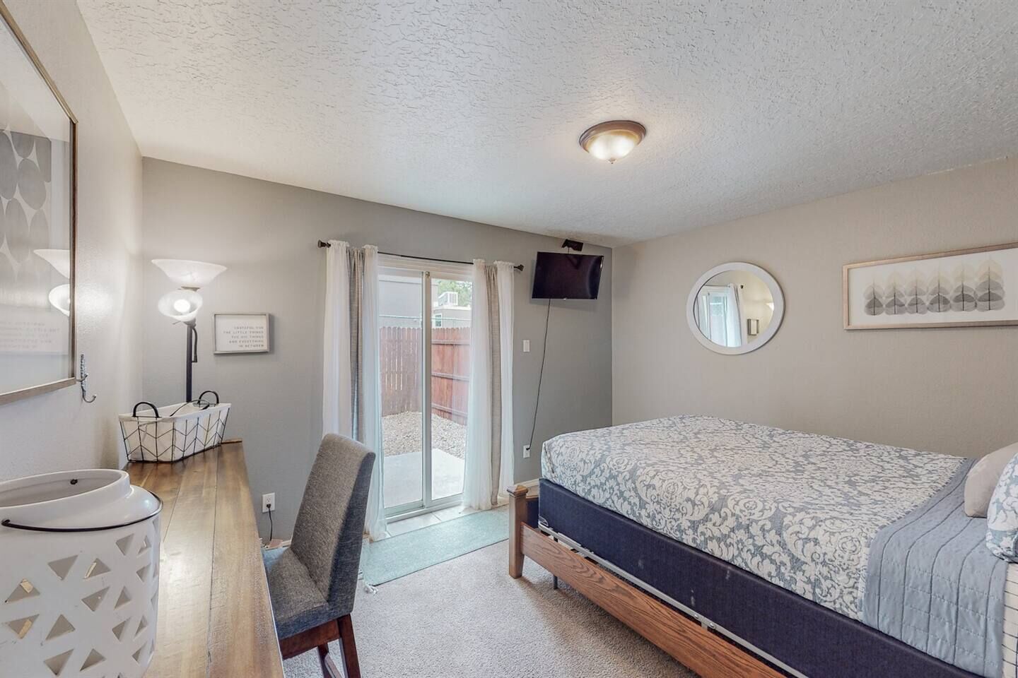 A bedroom with a bed, a desk, a chair, a TV, and a bathroom.