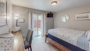 A bedroom with a bed, a desk, a chair, a TV, and a bathroom. - Mountain Road Hideaway, near Old Town (Albuquerque)