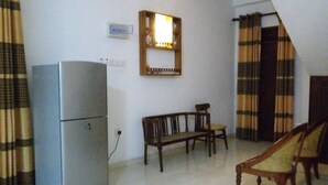 A compact living space with a refrigerator, a bench, and a chair. - sinhagiri hotel and restaurant (Tangalle)