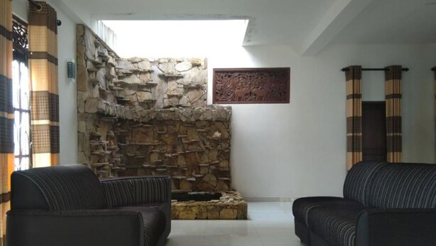 A living room with two sofas, a stone wall, and a fireplace. - sinhagiri hotel and restaurant (Tangalle)