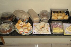 A buffet table with various food items including sandwiches, pastries, and desserts.