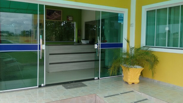 A reception area with a glass door, a potted plant, and a sign above the door. - Hotel KM 73 (Araquari)