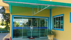 A hotel entrance with a glass door, a small outdoor seating area, and a potted plant. - Hotel KM 73 (Araquari)