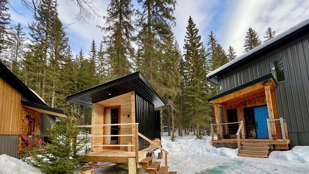Two cabins with wooden exteriors, a deck, and a snowy forest background. - The Stag Chalet,  new Sauna in the forest! Fast wifi! (Golden)