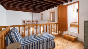 Una habitación acogedora con techo de madera, un sofá con cojines a rayas, una mesita y un banco de madera.
