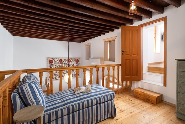 Une pièce chaleureuse avec un plafond en bois, un canapé agrémenté de coussins à rayures, une petite table et un banc en bois.