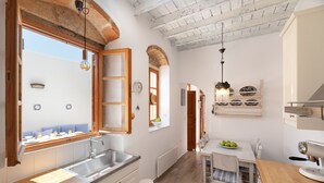Una cocina moderna con un ventanal grande, armarios blancos y una zona de comedor con una mesa y sillas.