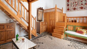 Una escalera de madera que conduce a un dormitorio estilo altillo con un banco verde y un espejo decorativo.