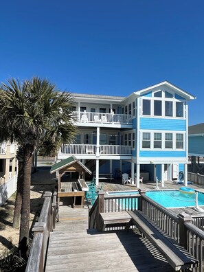 A multi-story building with a pool, wooden deck, and outdoor seating. - 7 BR, 7.5 Baths Oceanfront with Pool and Hot Tub! Book your week of Permanent Waves!! (Brunswick)
