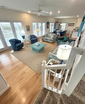 A spacious living room with a high ceiling, a ceiling fan, and a staircase leading to an upper level. - 5 bedrooms, 5 bathrooms. Oceanfront with oceanside screened in porch and pet friendly. (Brunswick)