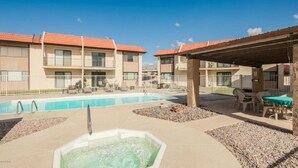 A hotel with a swimming pool, outdoor seating, and a hot tub.